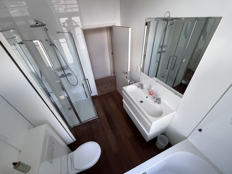 Second bathroom with glass walk-in shower, washbasin and toilet on dark wooden flooring