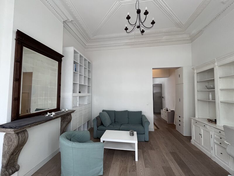 Living room with antique wood-framed mirror, chandelier and period ceiling mouldings in an 1860 Brussels house