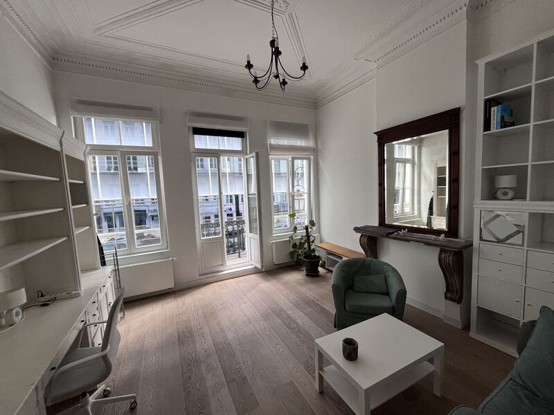 Bright living room with marble fireplace, bay window and wooden floor in a Brussels Grand Place apartment