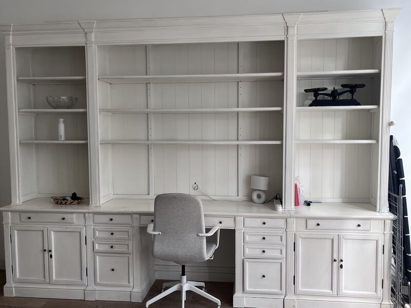 Built-in white bookshelves and desk workspace with office chair in the apartment living room