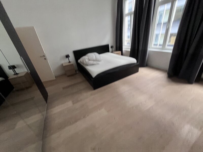 Master bedroom with double bed, wooden floor and large windows in the Brussels Grand Place apartment