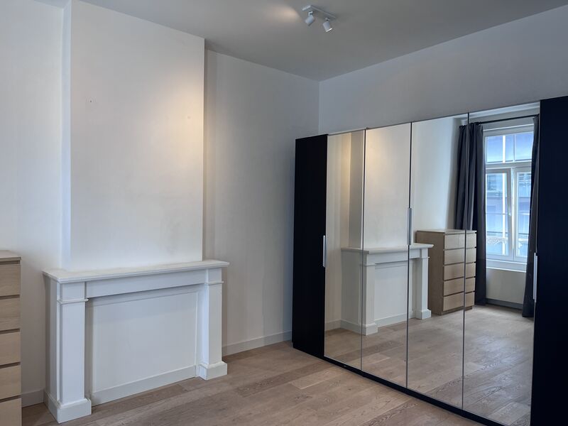Master bedroom with full-height mirrored wardrobe, white fireplace mantel and wooden floor