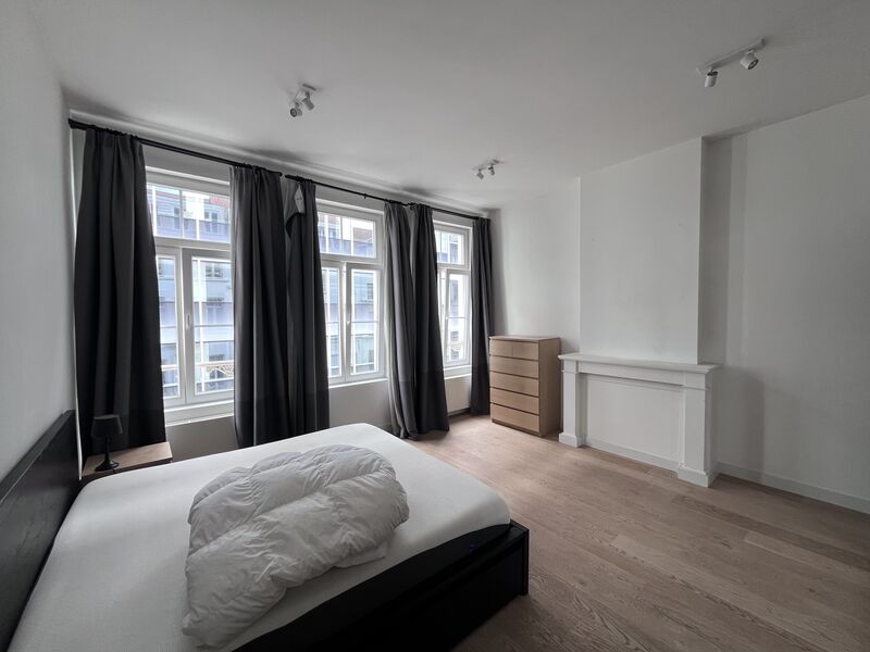 Master bedroom filled with daylight from three tall windows with blackout curtains and a chest of drawers