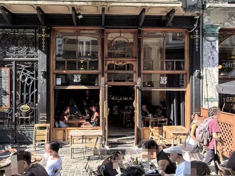 The dark timber and ironwork shopfront of Fin de Siècle on Rue des Chartreux, with terrace tables and diners at the open windows