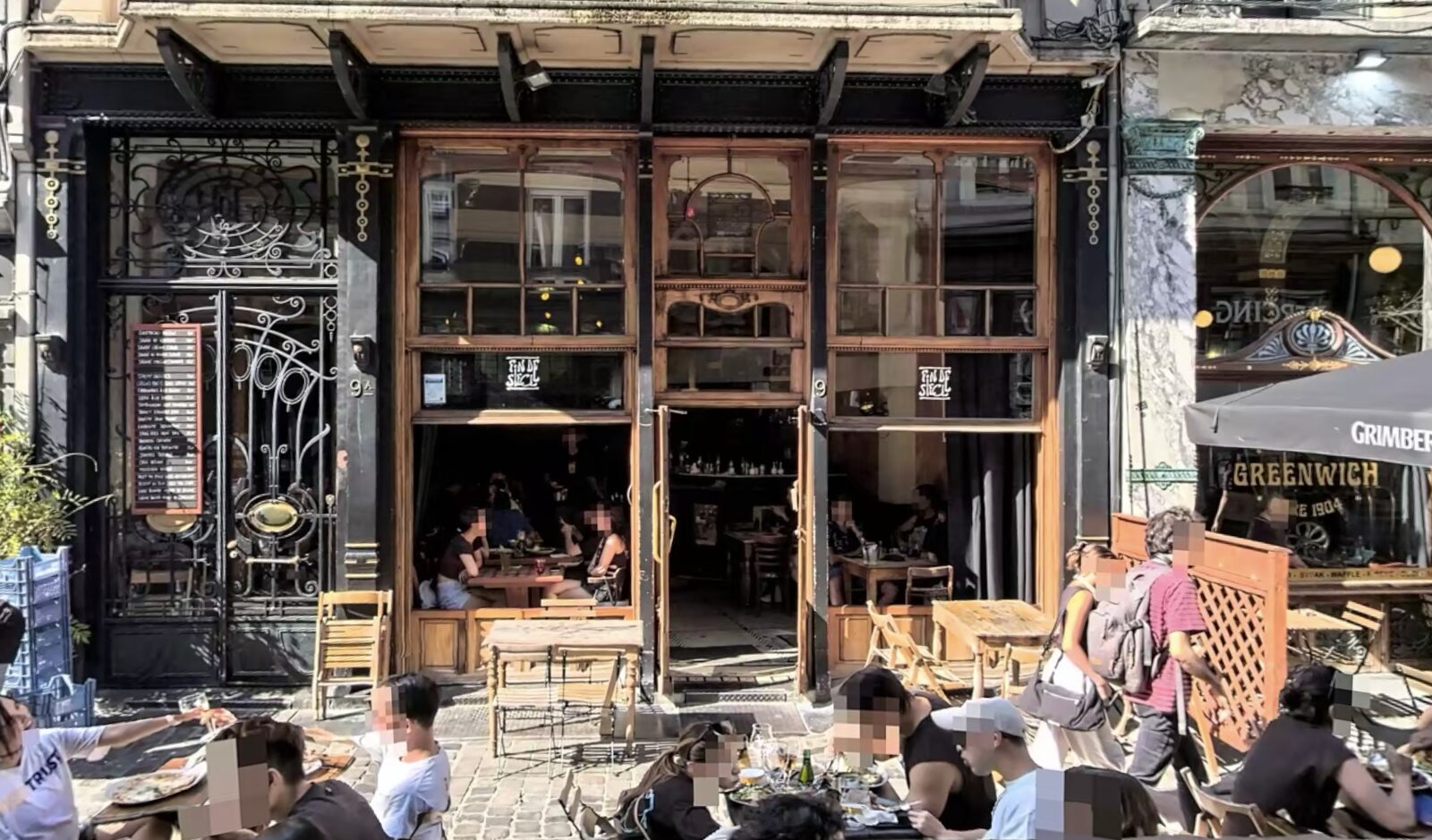The dark timber and ironwork shopfront of Fin de Siècle on Rue des Chartreux, with terrace tables and diners at the open windows