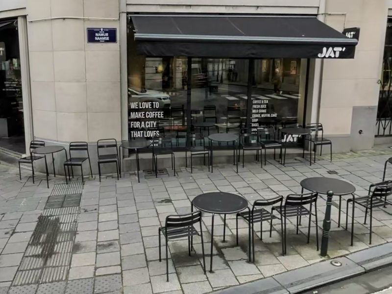 The corner shopfront of Jat' Café on Rue de Namur in Brussels, its black awning and pavement tables set out along the street