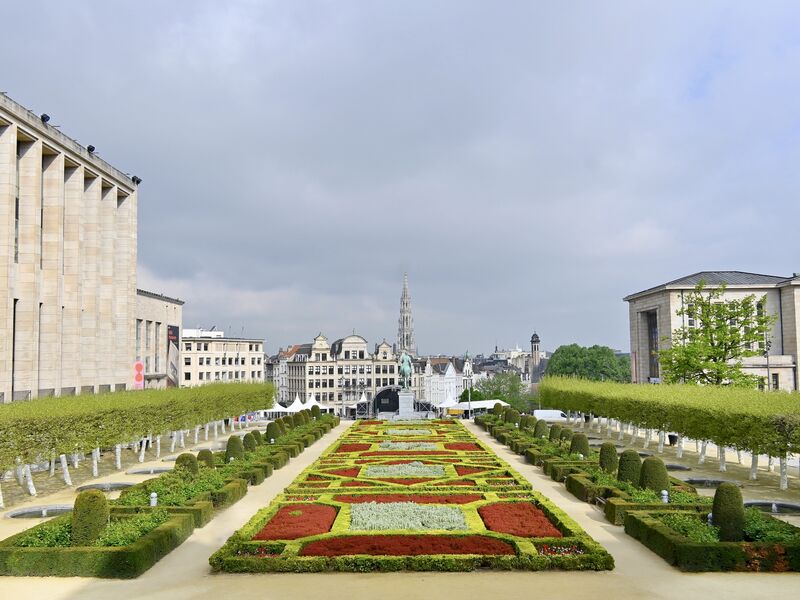 The formal garden of the Mont des Arts in Brussels seen from above, with clipped hedges and flowerbeds leading down towards the city