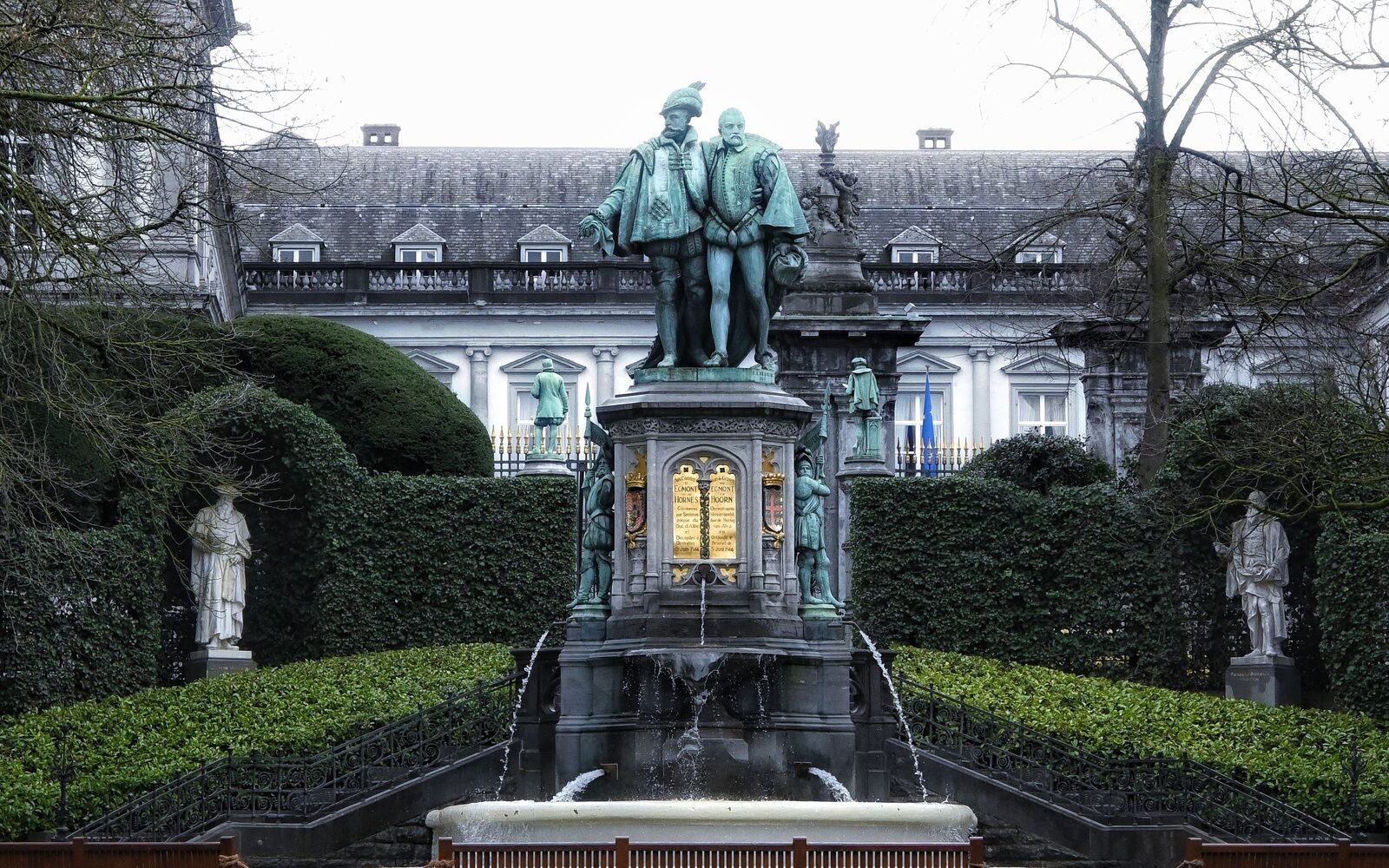 The Egmont and Hoorn monument in the Square du Petit Sablon in Brussels, water falling from the plinth into a stone basin, with clipped hedges and bronze statuettes on either side