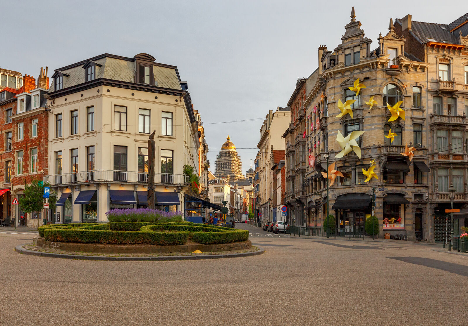 The Place du Grand Sablon in Brussels at dawn, its clipped hedges and corner cafés with the dome of the Palais de Justice beyond