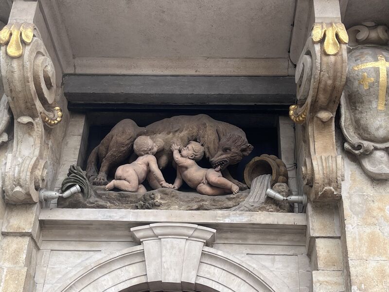 A stone relief above the door of La Louve: the she-wolf standing over Romulus and Remus, who reach up to suckle.