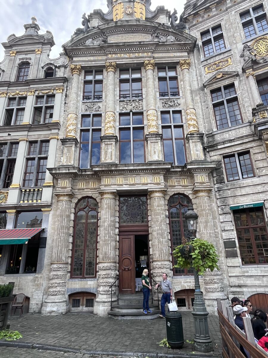 The Maison des Brasseurs on the Grand-Place, its Corinthian columns rising through two storeys to a pediment carrying gilded arms, with an arched doorway at the centre.