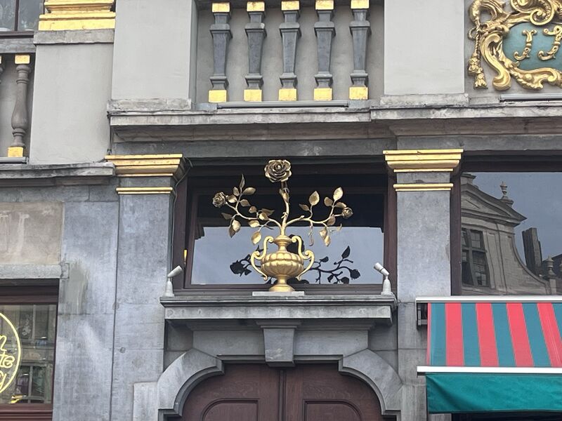 The gilded emblem of La Rose: a rose on a leafy branch rising from an urn, mounted above the doorway.