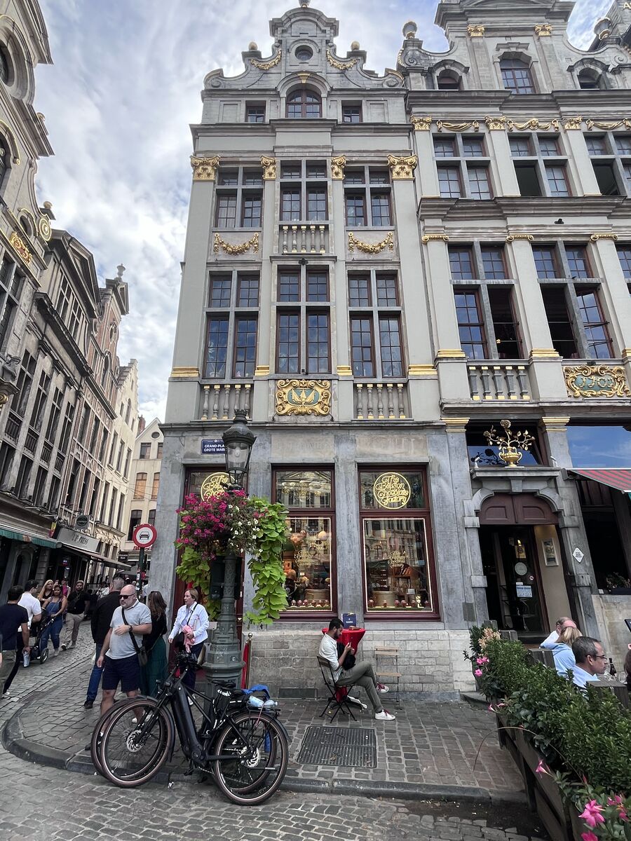 Le Mont Thabor on the Grand-Place, gilded swags across its facade and a shop at street level, with the Grand-Place street sign on the corner.