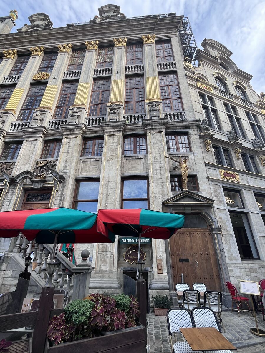 The Maison des Ducs de Brabant seen along its front, a continuous row of gilded pilasters above the Cave du Roy restaurant, with a gilded statue on the pedestal at the centre.