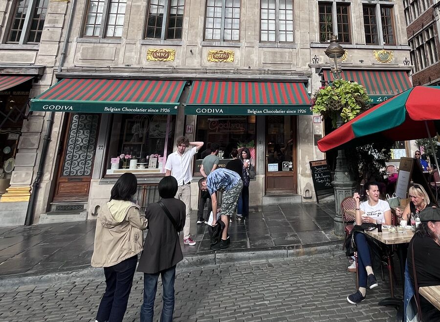 The two Godiva shopfronts of Joseph and Anne on the Grand-Place, the door numbers 22 and 21 beside them and the gilded cartouches lettered Anna and Joseph on the storey above.