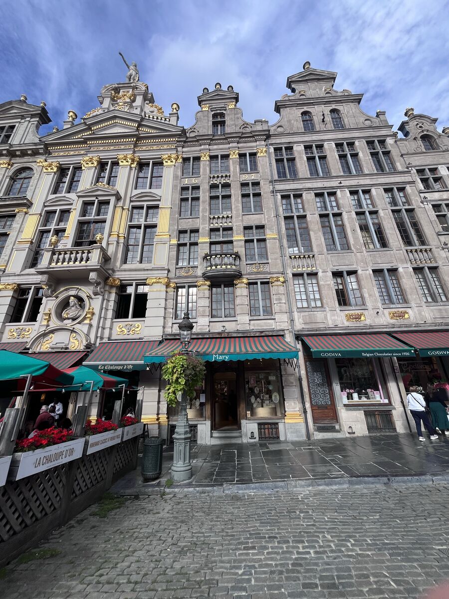 The Mary chocolate shop at Grand-Place 23 between its neighbours, La Chaloupe d'Or's terrace to the left and the two Godiva windows to the right.