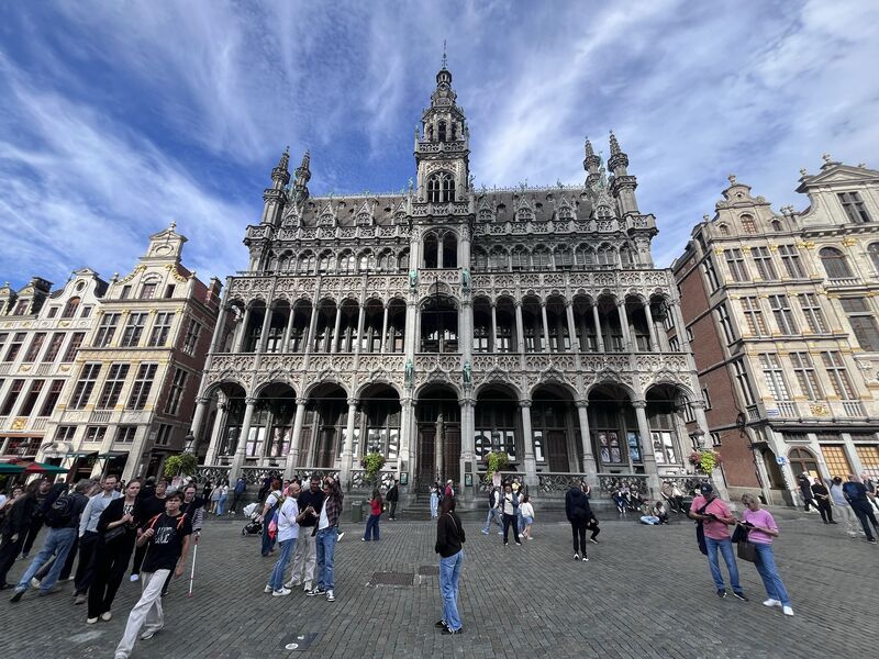The King's House across the cobbles of the Grand-Place, its arcaded front and open belfry above, with visitors crossing in front of it.